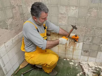 Čovjek skida pločice sa čekićem